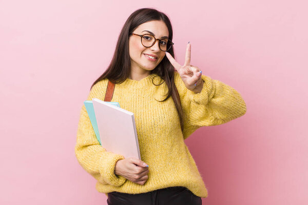 young pretty woman smiling and looking friendly, showing number two. university student concept