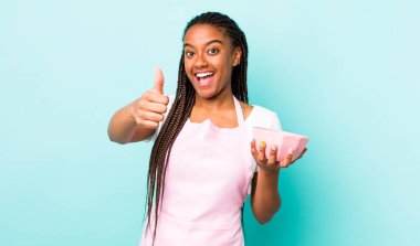 young adult black woman feeling proud,smiling positively with thumbs up. empty bowl concept