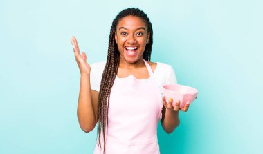 young adult black woman feeling happy and astonished at something unbelievable. empty bowl concept