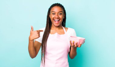 young adult black woman feeling happy and pointing to self with an excited. empty bowl concept