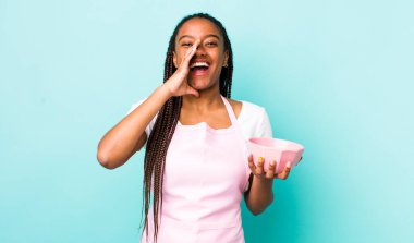 young adult black woman feeling happy,giving a big shout out with hands next to mouth. empty bowl concept