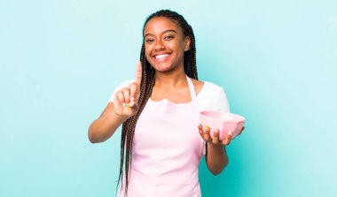 young adult black woman smiling proudly and confidently making number one. empty bowl concept