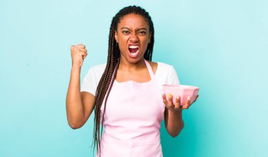 young adult black woman shouting aggressively with an angry expression. empty bowl concept