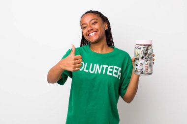 young adult black woman feeling proud,smiling positively with thumbs up. volunteer and donation concept