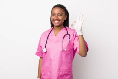 young adult black woman feeling happy, showing approval with okay gesture. veterinarian concept