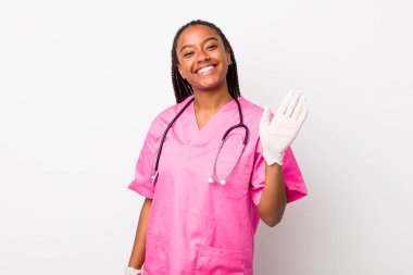 young adult black woman smiling happily, waving hand, welcoming and greeting you. veterinarian concept