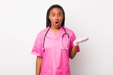 young adult black woman looking surprised and shocked, with jaw dropped holding an object. veterinarian concept