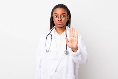 young adult black woman looking serious showing open palm making stop gesture. physician concept