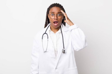young adult black woman looking happy, astonished and surprised. physician concept