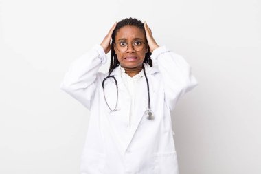 young adult black woman feeling stressed, anxious or scared, with hands on head. physician concept
