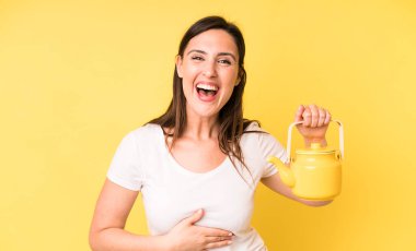 Genç ve güzel bir kadın komik bir şakaya yüksek sesle gülüyor. Sıcak kahve ya da çay konsepti