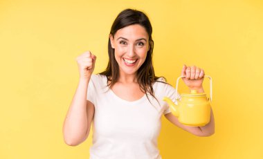 Genç ve güzel bir kadın şok olmuş hissediyor, gülüyor ve başarıyı kutluyor. Sıcak kahve ya da çay konsepti