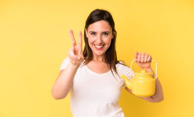 Genç ve güzel bir kadın gülümsüyor ve mutlu görünüyor. Zafer ya da barış işareti yapıyor. Sıcak kahve ya da çay konsepti