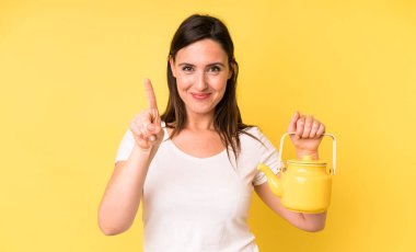 Genç ve güzel bir kadın gülümsüyor ve arkadaş canlısı görünüyor. Bir numarayı gösteriyor. Sıcak kahve ya da çay konsepti