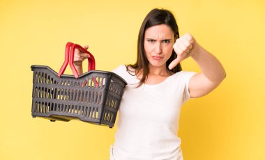 Genç ve güzel bir kadın kızmış, baş parmağını kaldırmış. Alışveriş sepeti konsepti