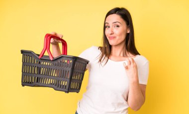 Genç ve güzel bir kadın kibirli, başarılı, pozitif ve gururlu görünüyor. Alışveriş sepeti konsepti