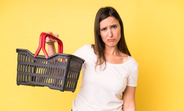 Genç ve güzel bir kadın üzgün ve mızmızlanıyor. Mutsuz bir bakışı var ve ağlıyor. Alışveriş sepeti konsepti