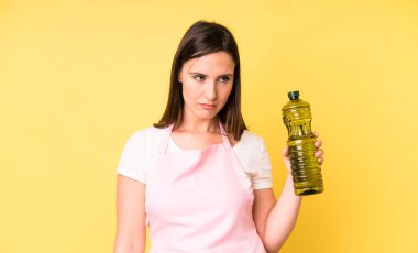 Genç ve güzel bir kadın üzgün, üzgün ya da kızgın hissedip yan tarafa bakıyor. Zeytinyağlı ev aşçısı