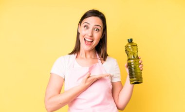 Genç ve güzel bir kadın neşeli bir şekilde gülümsüyor, mutlu hissediyor ve bir konsept gösteriyor. Zeytinyağlı ev aşçısı