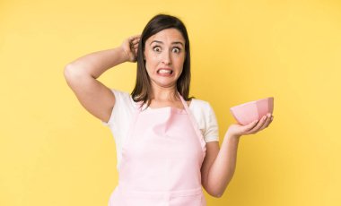 Genç ve güzel bir kadın stresli, endişeli ya da korkmuş hissediyor, elleri başının üstünde. Ev aşçısı konseptinde yemek pişirmek