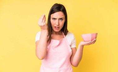 Genç ve güzel bir kadın kapiş ya da para hareketi yapıp sana ödemeni söylüyor. Ev aşçısı konseptinde yemek pişirmek