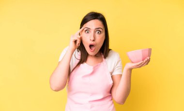 Genç ve güzel bir kadın şaşırmış görünüyor, yeni bir düşünce, fikir ya da konsept fark ediyor. Ev aşçısı konseptinde yemek pişirmek