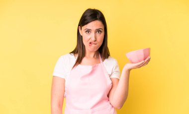 Kafası karışmış ve kafası karışmış genç ve güzel bir kadın. Ev aşçısı konseptinde yemek pişirmek