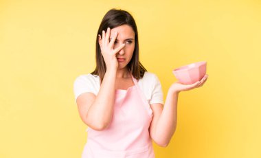 Genç ve güzel bir kadın bıkkın, yorgun ve uykulu hissediyor. Ev aşçısı konseptinde yemek pişirmek