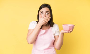 Genç ve güzel bir kadın şok olmuş bir şekilde elleriyle ağzını kapatıyor. Ev aşçısı konseptinde yemek pişirmek