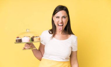 Neşeli ve asi tavırları olan, şaka yapan ve dilini dışarı çıkaran genç ve güzel bir kadın. Ev yapımı kek konsepti