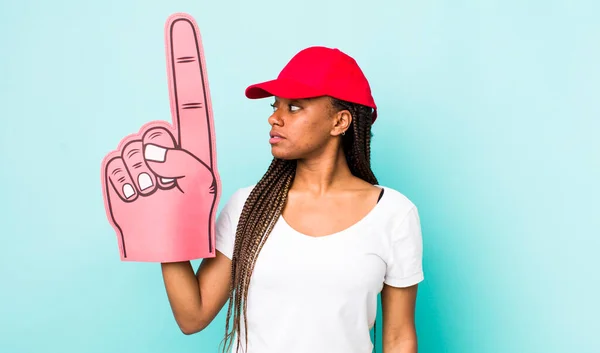 young adult black woman on profile view thinking, imagining or daydreaming. number one hand fan concept