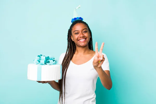 young adult black woman smiling and looking happy, gesturing victory or peace. birthday concept