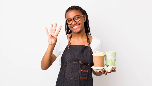 young adult black woman smiling and looking friendly, showing number four. take away coffees concept