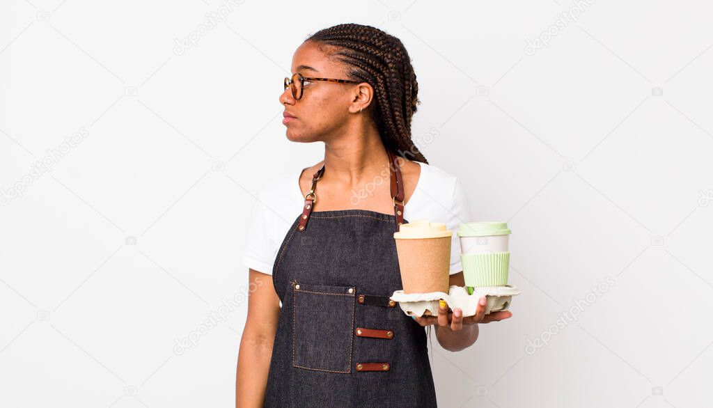 young adult black woman on profile view thinking, imagining or daydreaming. take away coffees concept