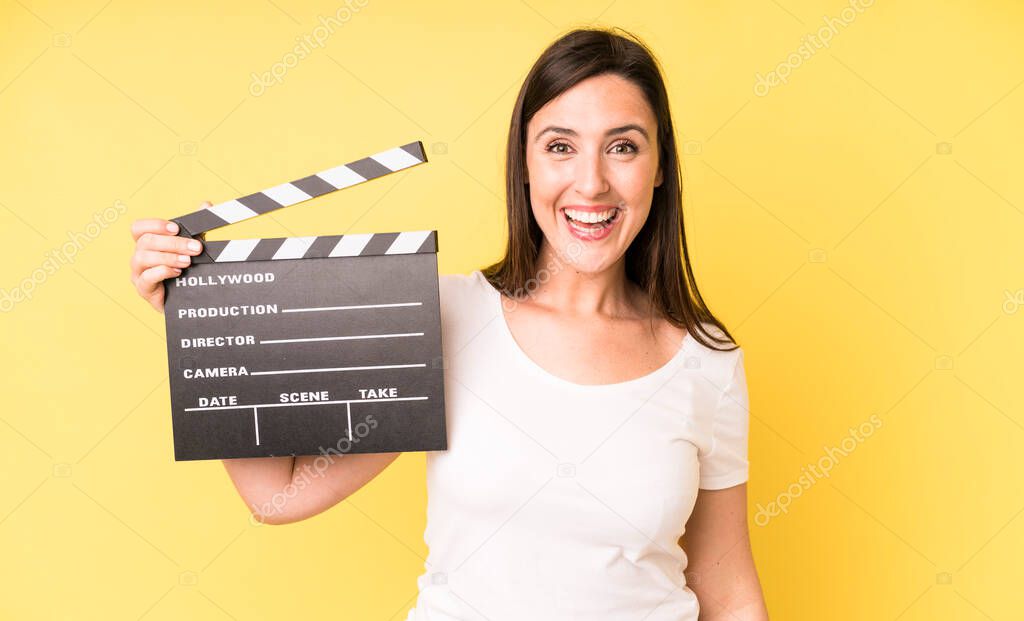 young adult pretty woman looking happy and pleasantly surprised. cinema clapper concept