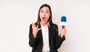 Genç ve güzel bir kadın son derece şaşkın ve şaşırmış hissediyor. Bir mikrofon konseptine sahip sunucu