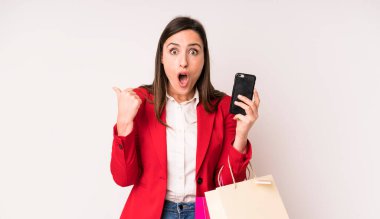 Genç ve güzel bir kadın inançsızlıktan şaşkın şaşkın bakıyor. Alışveriş torbaları konsepti