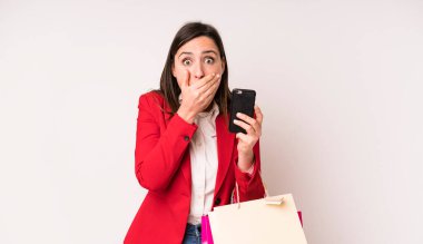 Genç ve güzel bir kadın şok olmuş bir şekilde elleriyle ağzını kapatıyor. Alışveriş torbaları konsepti