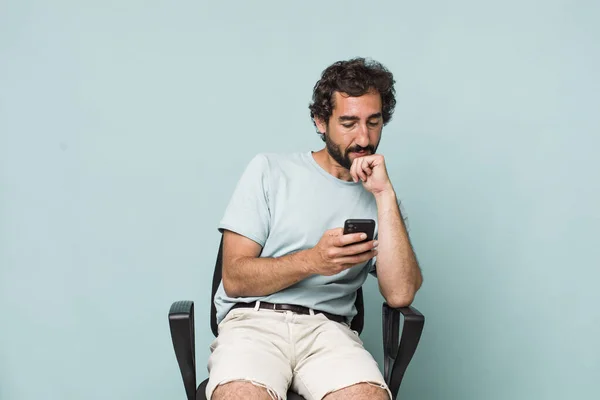 Молодий Дорослий Іспаномовний Божевільний Чоловік Використовує Свій Телефон Сидячи Стільці — стокове фото