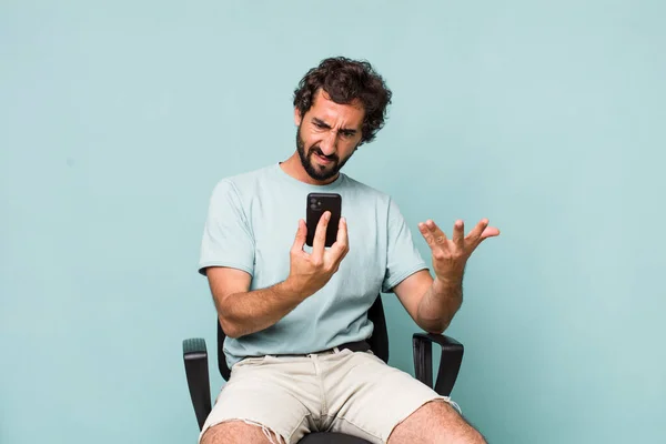 Joven Adulto Hispano Loco Hombre Usando Teléfono Sentado Una Silla —  Fotos de Stock