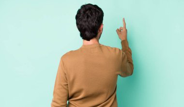 Genç, Latin asıllı, dikiz aynasında duran ve objeye işaret eden adam.