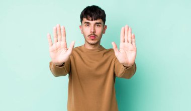 Genç, Latin asıllı, ciddi, mutsuz, kızgın ve hoşnutsuz görünen bir adam.