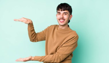 Genç, İspanyol asıllı, gülümseyen, mutlu, pozitif ve tatmin olmuş, fotokopi alanında nesne ya da konsept tutan