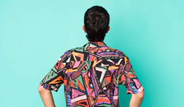 Genç, İspanyol asıllı, kafası karışık ya da dolgun ya da şüphe ve soru dolu, merak içinde, elleri kalçasında, dikiz aynasından