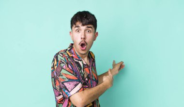 Genç, Latin asıllı, şaşkın ve şaşırmış bir genç. Bir yandan şaşkınlık dolu, ağzı açık bir bakışla fotokopi alanını işaret ediyor.