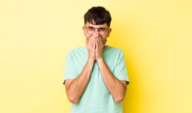 Genç, yetişkin İspanyol adam mutlu, neşeli, şanslı ve şaşkın görünüyor iki eliyle ağzını kapatıyor.