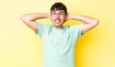 Genç, İspanyol asıllı bir adam stresli, endişeli, endişeli ya da korkmuş hissediyor. Elleri başının üstünde, hatayla panikliyor.