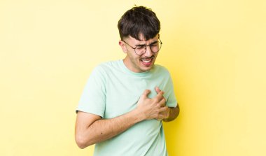 Genç İspanyol bir adam üzgün, yaralı ve kalbi kırık görünüyor, iki elini de kalbe yakın tutuyor, ağlıyor ve bunalımda.