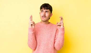 Genç, Latin bir adam endişeyle dua ediyor ve endişeli bir bakışla iyi şanslar diliyor.