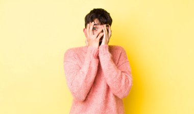 Genç, İspanyol bir adam korkmuş ya da utanmış hisseder. Gözleri yarı kapalı, yarı çıplak bir şekilde dikizler ya da gözetler.